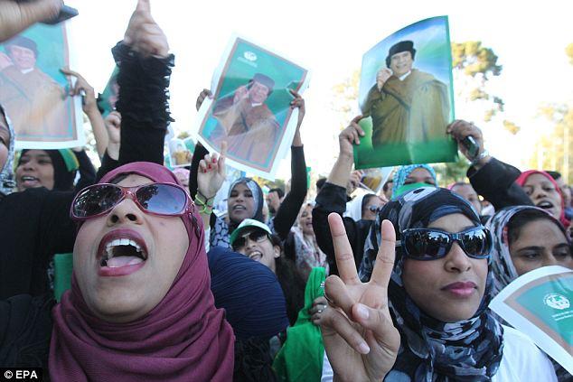 Libyan women hold portraits of Colonel Gaddafi during a pro-regime protest in Tripoli yesterday