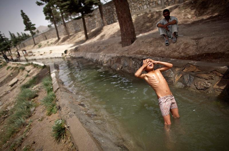 Baignade - Les mains sur le visage et les yeux fermés, il se laisse tomber en arrière. En Afghanistan, cet enfant s’offre une séance de baignade dans un courant d’eau, sous le regard bienveillant d’un parent. Une façon de profiter de l’été et de se rafraichir tant bien que mal. Ici à Kaboul, la capitale, les amplitudes thermiques journalières de plus de 25 °C sont assez fréquentes.