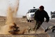 Rebel fighters jump away from shrapnel during heavy shelling by forces loyal to Libyan leader Muammar Gaddafi near Bin Jawad
