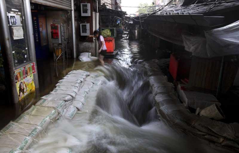 <b></div>Riz thaï</b>. Dérisoires remparts que ces sacs de riz emplis de sable et entassés au ras des habitations pour retarder leur inondation. Cela fait maintenant dix jours que des masses d’eau boueuse s’infiltrent dans tout Bangkok, mais ce quartier du centre-ville est tout de même privilégié : la hauteur de l’eau n’impose pas son évacuation, et elle n’est pas suffisante non plus pour qu’on y voie flotter parfois le dos inquiétant de l’un des nombreux crocodiles échappés des fermes d’élevage du nord. Les habitants sont donc restés, et ils ont échappé au pire : les grandes marées de dimanche dernier n’ont pas aggravé la situation, contrairement à ce que tout le monde redoutait.