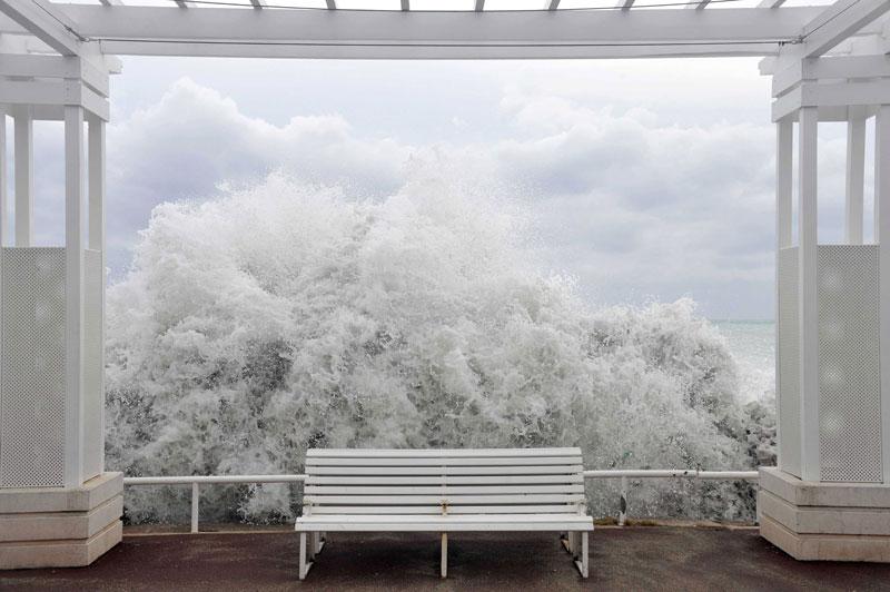 <b></div>Brise de Nice</b>. Ce cliché est probablement l’un des plus beaux que nous ayons jamais publiés. On croirait un tableau de Magritte, et c’est au «coup de mer» qui a déferlé le 8 novembre sur une partie de la Côte d’Azur que nous le devons. Le décor, naturel, est celui de la Promenade des Anglais, à Nice. La vague est très haute puisqu’elle a déjà traversé la plage, mais son écume se confond ici avec celle des nuages, encadrée par une architecture épurée dont elle ne franchit pas la barrière, éclaboussant tout d’un camaïeu de blancs qui respire la sérénité. Seul un peintre aurait pu normalement inventer un tel contraste avec la fureur des éléments, mais c’est un photographe qui l’a capturé. 