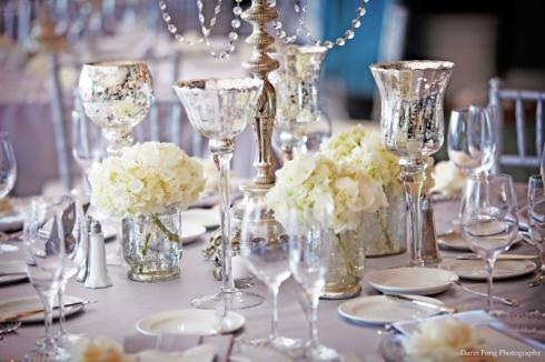 Succession de petits vases et de photophores en centre de table de mariage