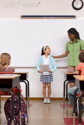 Image libre de droits: Girl reading report aloud in classroom