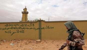 Un membre du CNT libyen passe devant des graffitis anti-Kaddafi à Bani Walid, en octobre 2011.