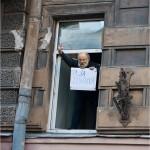 Vladimir Churov à la fenetre avec une pancarte je suis pour Poutine