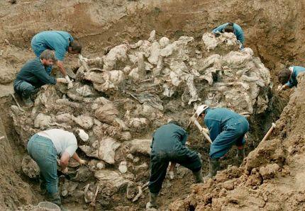 Des experts examinent une pile de corps en décomposition extraits d'une fosse commune le 24 juillet 1996, près du village de Pilica, à 300km au nord-est de Sarajevo. AFP PHOTO ODD ANDERSEN
 