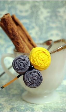 A duo of pale grey rosettes are made complete by the addition of a cheery yellow rosebud and a little black pearl for good measure. All are perched delicately on a thin silver metal headband measuring 3 mm wide.