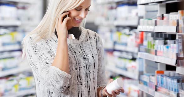 une femme dans une pharmacie tenant un téléphone portable