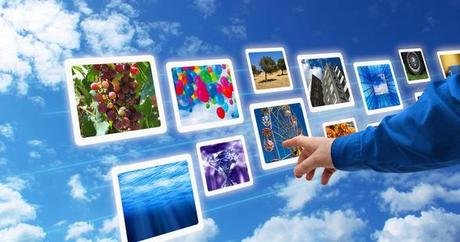 main qui touche des écrans sur fond de nuages