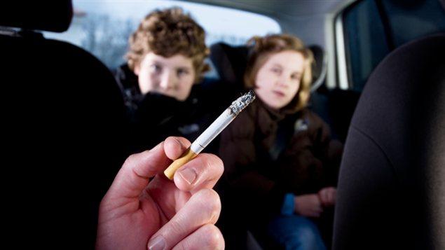 Une femme fume dans une voiture dont certains passagers sont des enfants.