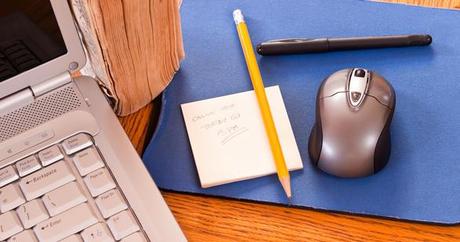 ordinateur, feuille de papier et crayon disposés sur un bureau