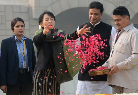 En Inde, Aung San Suu Kyi, adepte depuis toujours de la Non-Violence, se recueille sur le Mémorial de Gandhi et jette des centaines de pétales de roses en son honneur