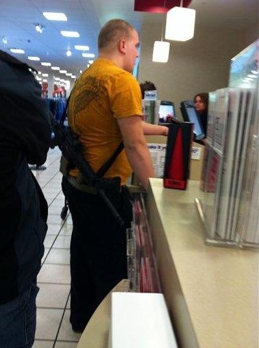 Un homme qui fait ses courses avec une arme sur l'épaule