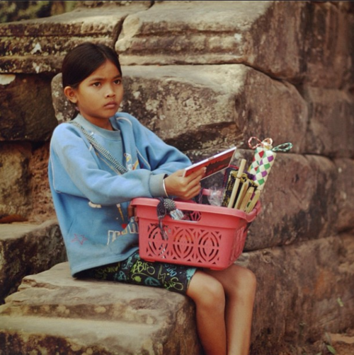 La fillette du Temple. 
“Chaque week-end, elle sera dans le temple à vendre des souvenirs aux touristes. Elle aime aller à l’école pendant la semaine et étonnamment, elle peut compter de 1 à 10 dans 10 langues différentes (ce sont les touristes qui le lui ont appris). Croyez-moi, tous ces enfants sont très intelligents! Si seulement ils avaient un système éducatif approprié…” - Source @oddessee84 sur Instagram