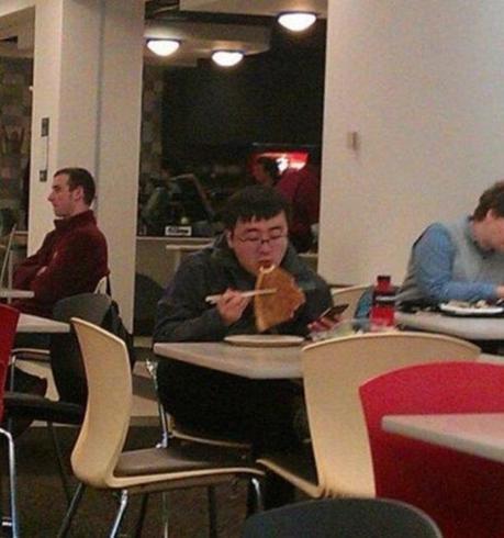 3. Un homme qui mange sa pizza avec des baguettes