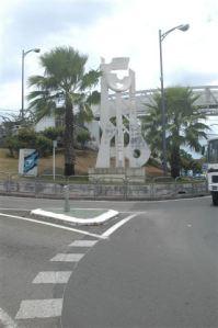 arbres, poteaux électriques, panneau publicitaire empêche la lecture de l'oeuvre