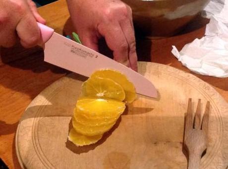 un couteau rose qui coupe une orange