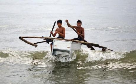 Deux jeunes philippins sur leur embarcation de fortune (un frigo et du bambou comme rames) après le passage du typhon Haiyan.