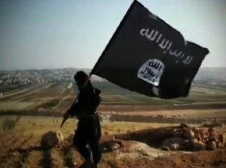 Groupe Al-Qaïda: Un homme tenant le drapeau de l'Etat islamique en Irak et al-Sham (ISIS) marche à travers une colline dans une vidéo de propagande pour l'organisation
