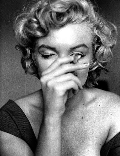 photgraphie de marilyn monroe portrait faisant un clin d'oeil et fumant une cigarette cheveux décoloré blonde platine sourire 