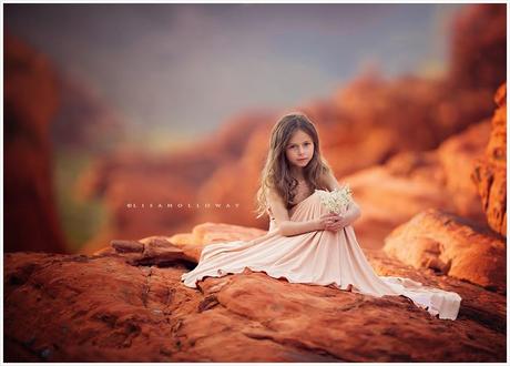 photo de Lisa Holloway représentant une jeune file en grande robe blanche assise sur des rochers