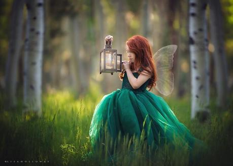 photo de Lisa Holloway représentant une jeune fille en robe verte et petite ailes d'anges tenant une lampe ancienne dans une forêt