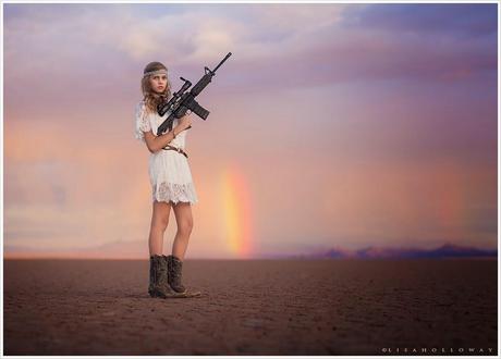 photo de Lisa Holloway représentant une jeune femme en courte robe blanche tenant un fusil d'assaut dans un désert