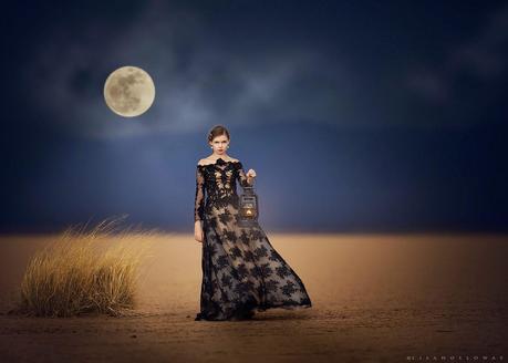 photo de Lisa Holloway représentant une jeune femme en robe en dentelle noire tenant un lampe dans un desert