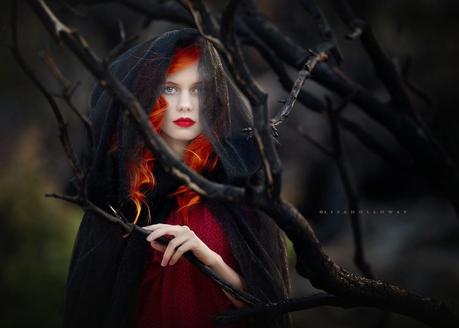 photo de Lisa Holloway représentant le portrait une jeune femme rousse en robe rouge derrière des branches