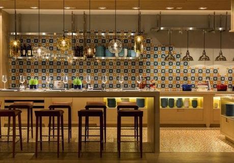 Une cuisine immense, avec une crédence en mosaïque colorée et un bar pour les invités avec des loupiotes industrielles au-dessus de leur tête © Pinterest