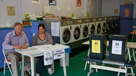 Poll clerks are seen in a public launderette being used as a polling station in Oxford, southern England