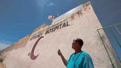 Un membre du personnel médical de l’hôpital Keysaney montre du doigt l’emblème du Croissant-Rouge de Somalie. © Pedram Yazdi/CICR