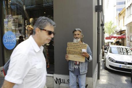 Un cadre d'entreprise passe devant un clochard dans les rues d'Athênes