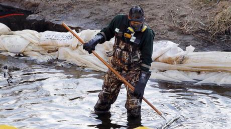 Un travailleur nettoie un film chimique sur l'eau dans Sand Creek, au nord de Denver, après une fuite de pétrole.