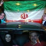 Iranian women wave the national flag during celebration in northern Tehran on July 14, 2015, after Iran's nuclear negotiating team struck a deal with world powers in Vienna. Iranians poured onto the streets of Tehran after the Ramadan fast ended at sundown Tuesday to celebrate the historic nuclear deal agreed earlier with world powers in Vienna. AFP PHOTO/ATTA KENARE