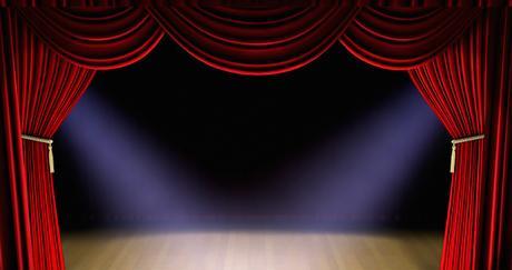 Theatre stage with red curtain and spotlights on the stage floor.