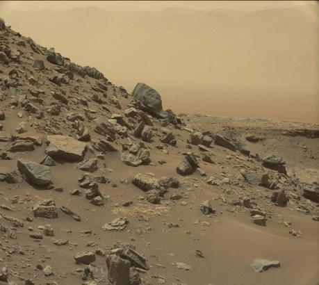 Sol 1.454 (8 septembre 2016). Première des cinq images spectaculaires du paysage de Far West que Curiosity arpente depuis août 2016. Des mille-feuilles de grès sont visibles de part et d’autre de cette zone appelée « Murray Butes » située à la base du mont Sharp. Constituées par le vent il y a plusieurs milliards d’années, elles ont été mises à jour par l’érosion éolienne. À l’arrière-plan, on aperçoit au loin malgré la brume orangée, les remparts du cratère Gale — Crédit : NASA, JPL-Caltech, MSSS