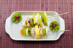 Two skewers full with colourful fruit on a table