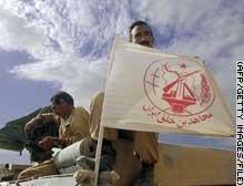 Des membres de l’OMPI affichent leur bannière en passant un point de contrôle américain en Irak, en 2003 (AFP).