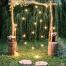 Une arche de mariage en bois habillée de lumière et de fleurs,  comme une porte féérique au milieu de la nature.