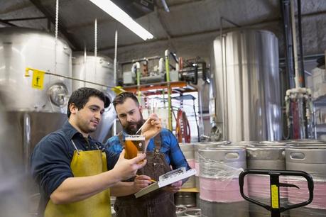 Deux travailleurs de la brasserie testent de la bière dans un bécher