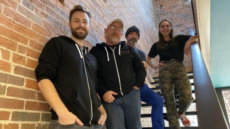 Quatre personnes posent dans une cage d'escalier.