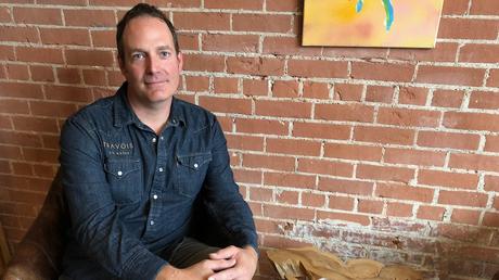 Jacques LeBlanc est assis sur une chaise devant un mu de brique.