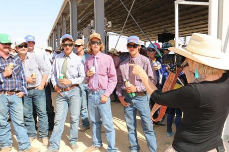 Une femme portant un chapeau à large bord prend la photo d'un groupe d'hommes portant tous un jean, une chemise et des chapeaux