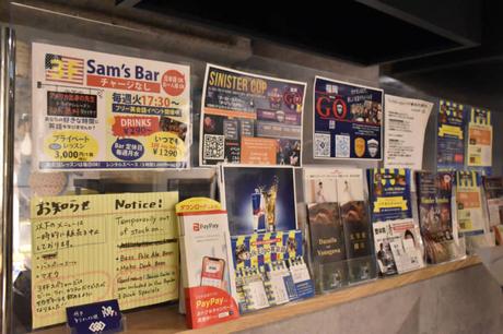 Un mur à lui: des tracts faisant la promotion de divers événements communautaires jalonnent les murs du bar Sam TalkEigo de Fukuoka. Le propriétaire Sultan 'Sam' Vidhani a déclaré que le plus difficile de la création de son entreprise était de trouver un propriétaire qui louerait à une personne non japonaise. | IRINA GRIGOROVICI
