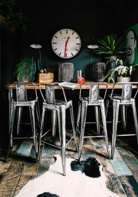 appartement noir salon salle à manger table haute style bar avec chaises industrielles parquet bois foncé