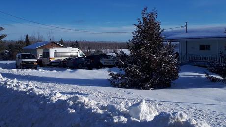 Vue extérieure d'une résidence, avec des voitures de la Sûreté du Québec.