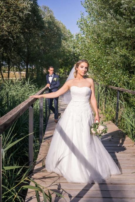Les mariés posent sur un pont de bois traversant une forêt de roseaux.