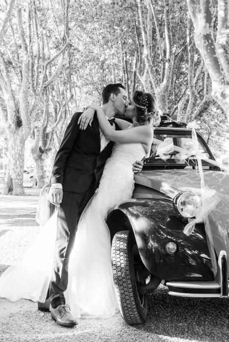 Extrait du mariage de Samia et Romain à Nîmes les deux mariés s'embrassent contre une voiture deux chevaux décorée pour le mariage