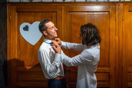 Extrait du mariage de Samia et Romain à Nîmes une garcçon d'honneur fixe le nœud papillon du marié